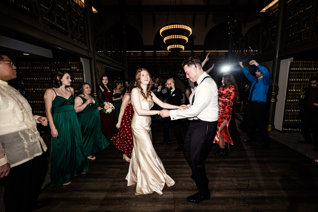Bride and groom dance at their Library at 190 wedding reception, surrounded by cheering guests