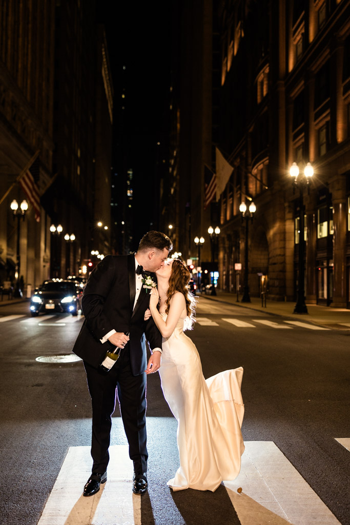 Newlyweds kiss at night on LaSalle Street in downtown Chicago