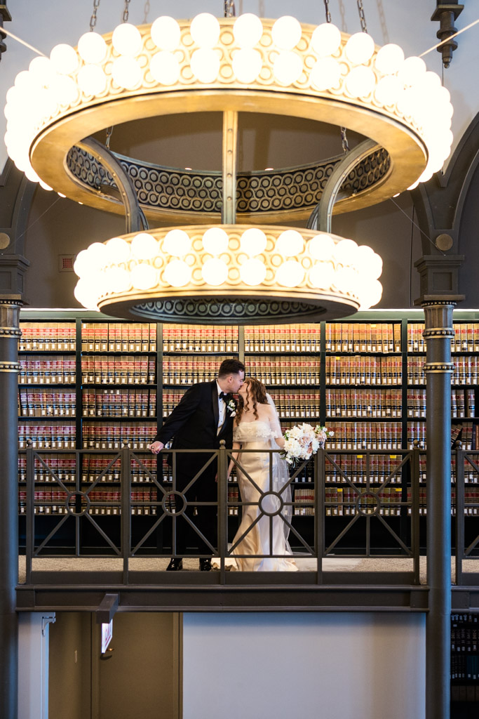 Bride and groom kiss on a book-lined balcony at The Library at 190 in downtown Chicago