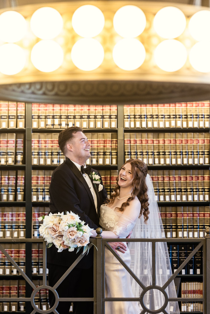 Bride and groom laugh in front of shelves filled with books at The Library at 190 in downtown Chicago