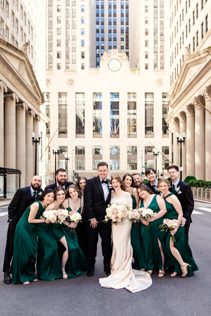 Portrait of wedding party outside The Library at 190 in downtown Chicago, with bridesmaids in green dresses and groomsmen in black suits