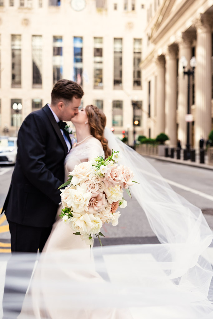 Creative photo of bride and groom kissing on a city street outside The Library at 190 in downtown Chicago with flowing veil