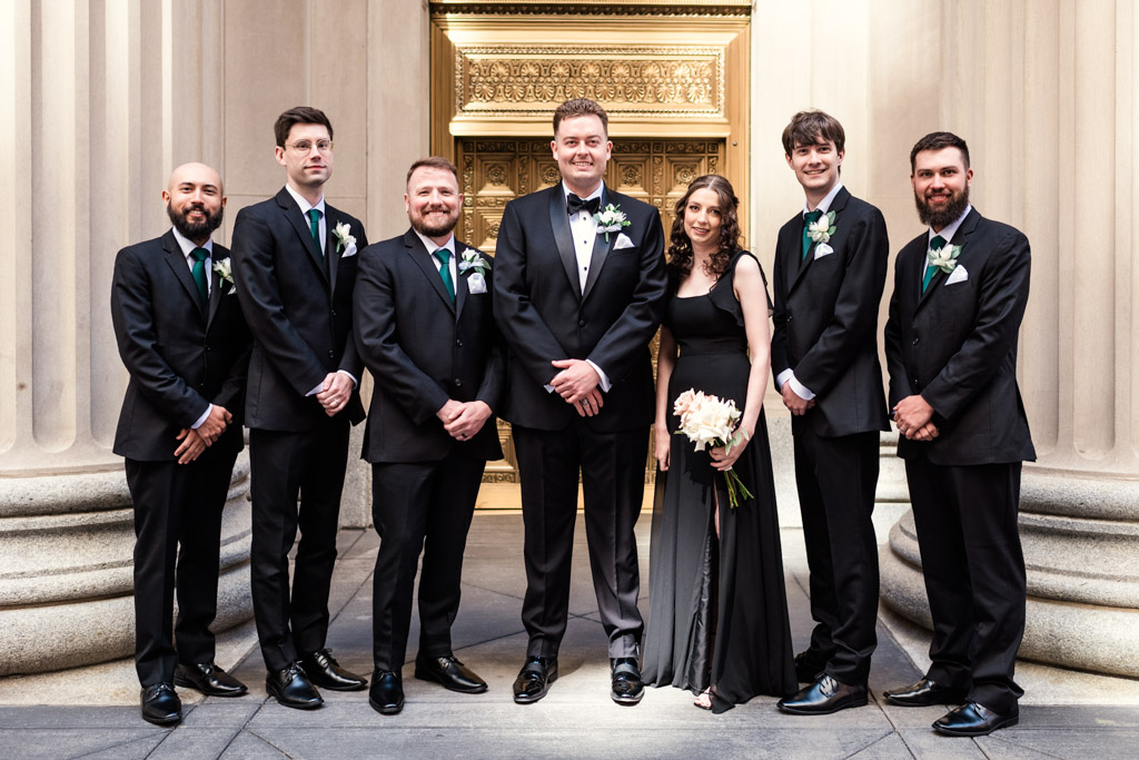 Portrait of groom and groomspeople in front of a golden door flanked by marble columns in downtown Chicago