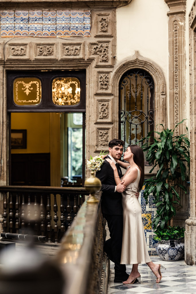 Couple embraces on a balcony with patterned tiles and elegant decor at La Casa de los Azulejos during their Mexico City elopement