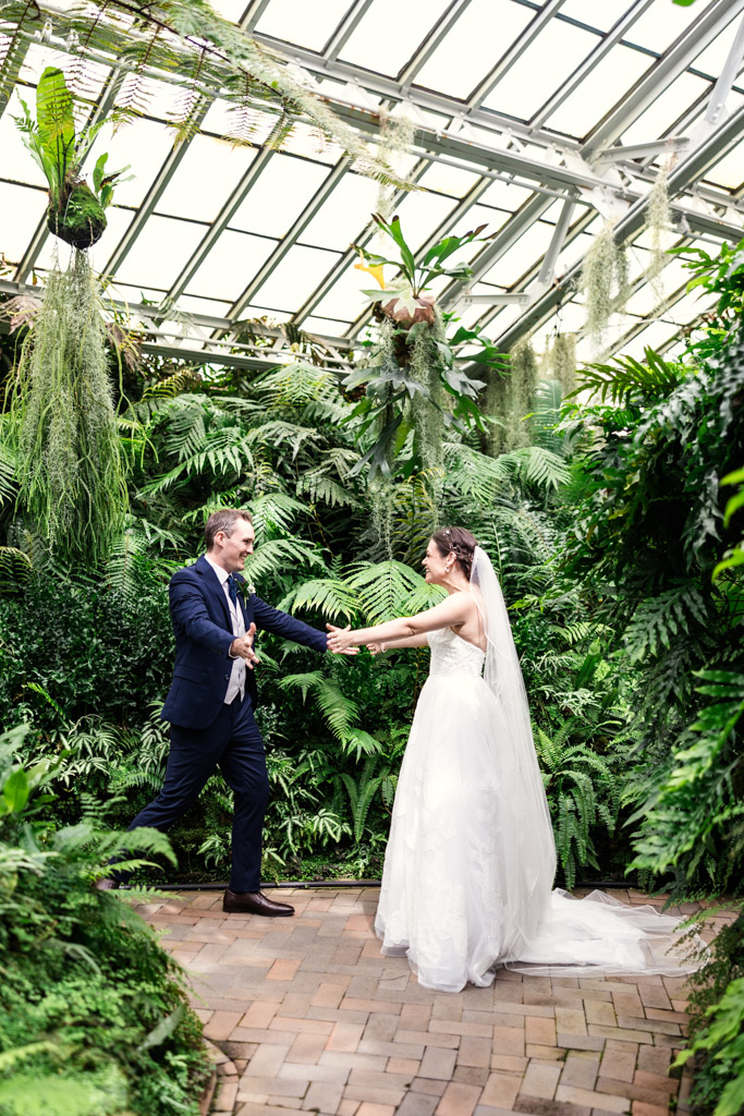 Bride and groom joyfully hold hands in Garfield Park Conservatory's Fern Room