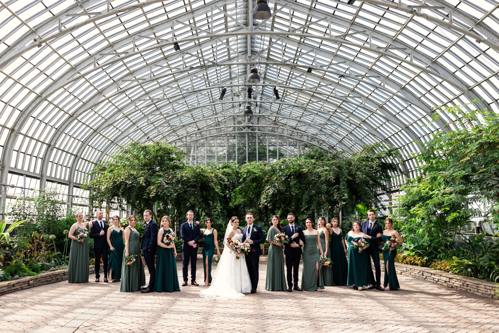 Portriat of wedding party in a large glass greenhouse at Garfield Park Conservatory with lush greenery in the background