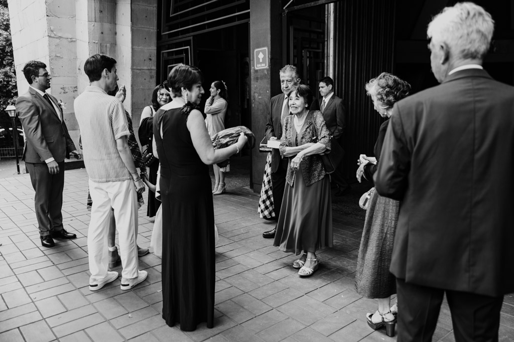 Black and white photo of bride and groom's parents along with other guests outside Parroquia San Cayetano before the wedding ceremony