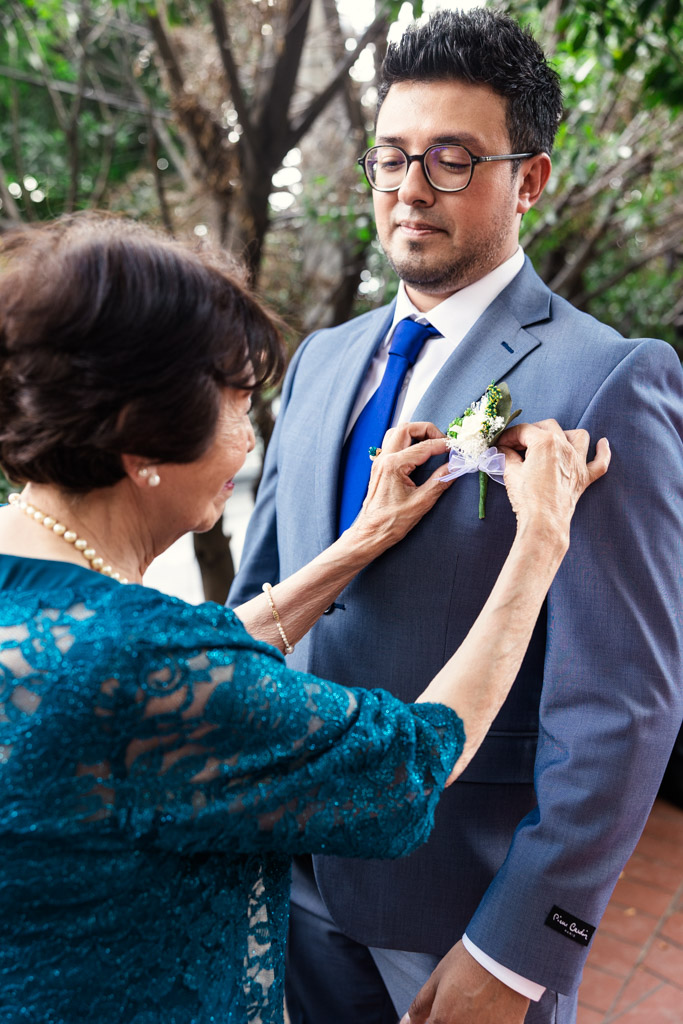 Groom's mother pins a boutonniere on her son's lapel before his wedding at Parroquia San Cayetano in Mexico City