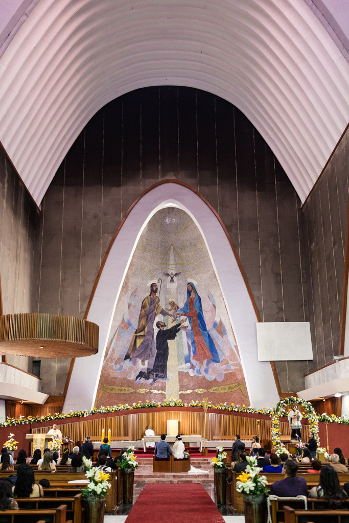 Bride and groom kneel before the altar at Parroquia San Cayetano during their wedding ceremony
