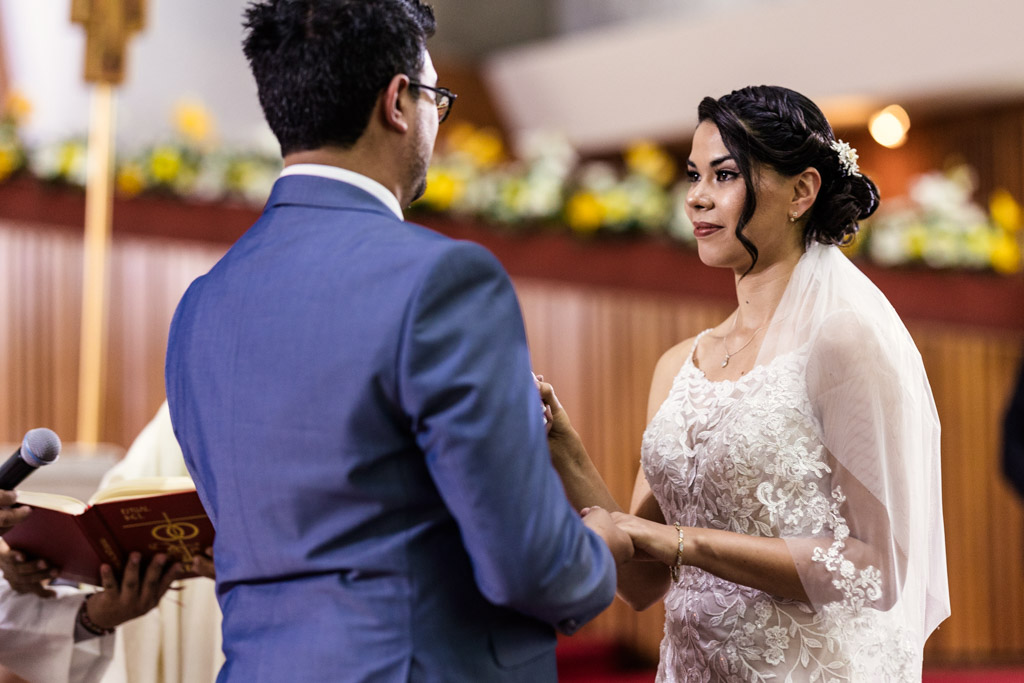 Bride and groom hold hands during their wedding ceremony at Parroquia San Cayetano