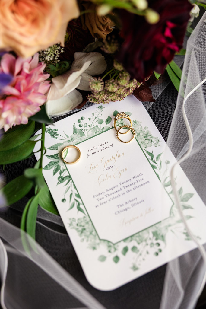 Wedding invitation with three gold rings, surrounded by flowers and bride's veil