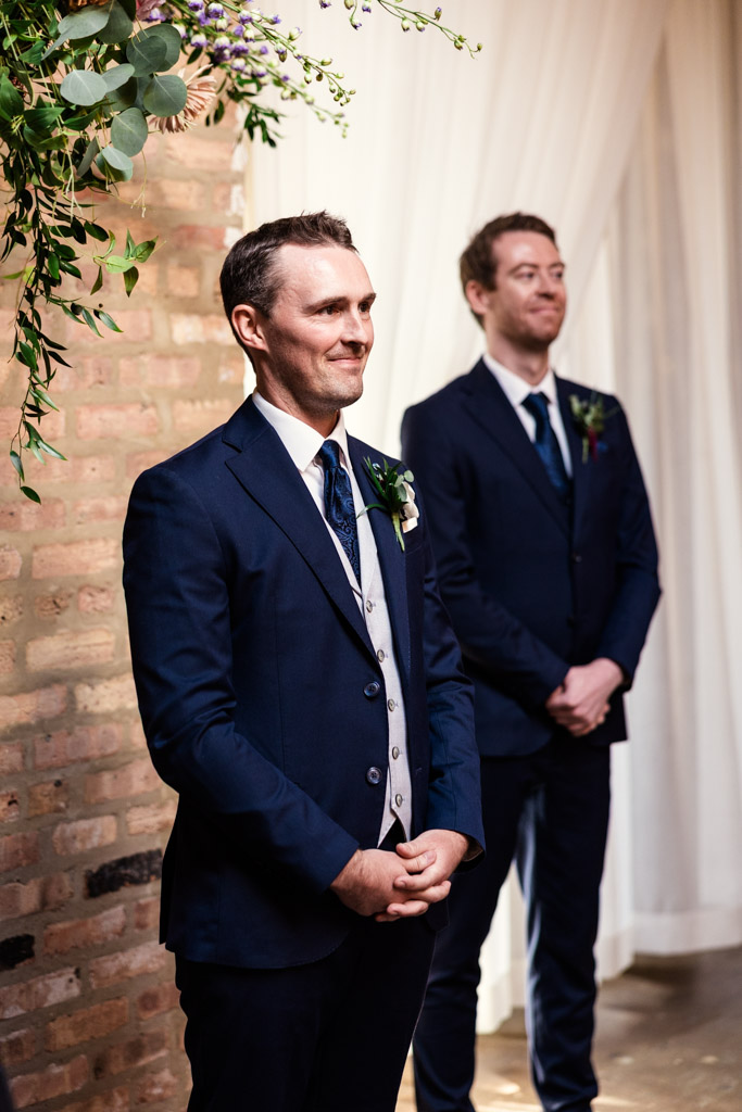 Groom watches the bride walk down the aisle during wedding ceremony at The Arbory Chicago