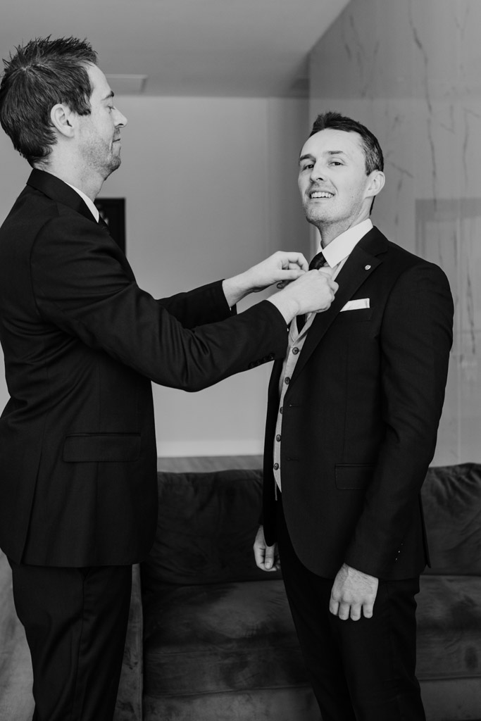 Best Man helps groom with his tie while getting ready for wedding celebration at The Arbory Chicago