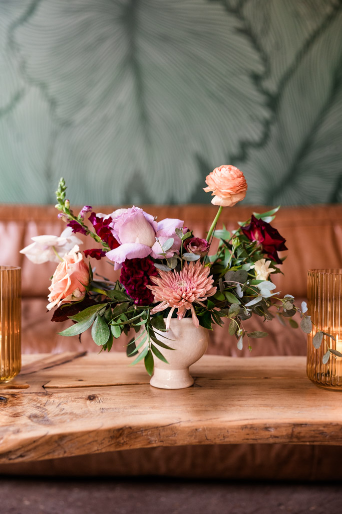 Detail photo of small vase of assorted flowers on a wooden table at The Arbory Chicago