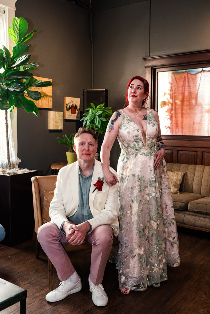 Portrait of bride in a floral dress standing beside a groom in a white jacket in a cozy, plant-filled room at Firehouse Chicago