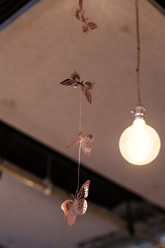 Paper butterflies hanging from a string near a lit bulb against a dim indoor ceiling at Firehouse Chicago