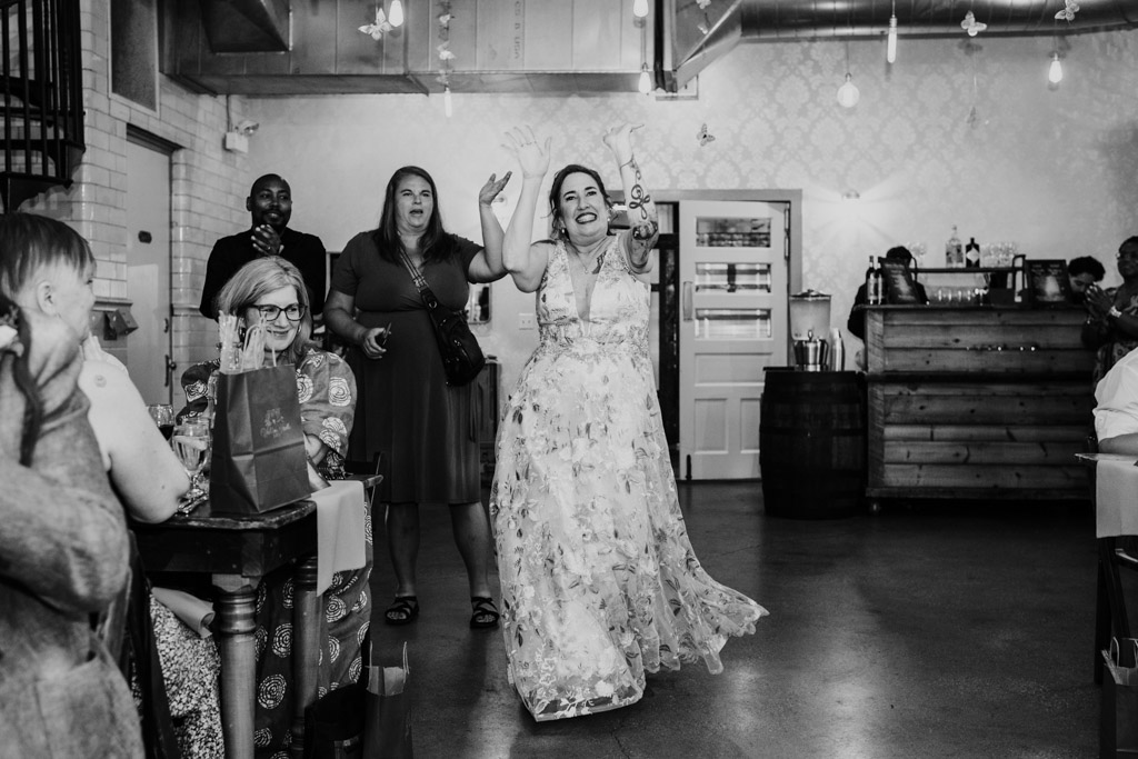 Black and white photo of bride in a floral dress dancing and smiling at Firehouse Chicago