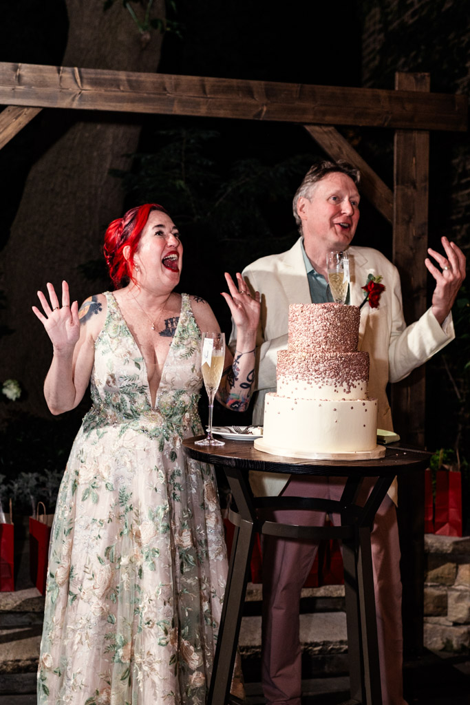 Newlywed couple stands by their tiered wedding cake during Firehouse Chicago reception