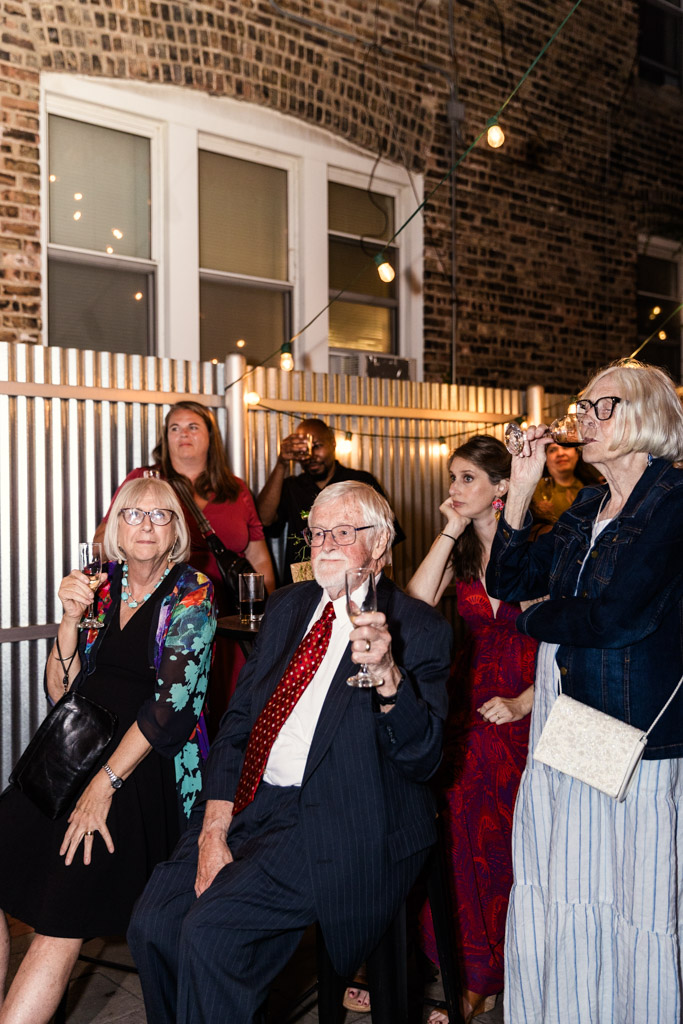 Guests sit and stand outside Firehouse Chicago at night during summer wedding reception