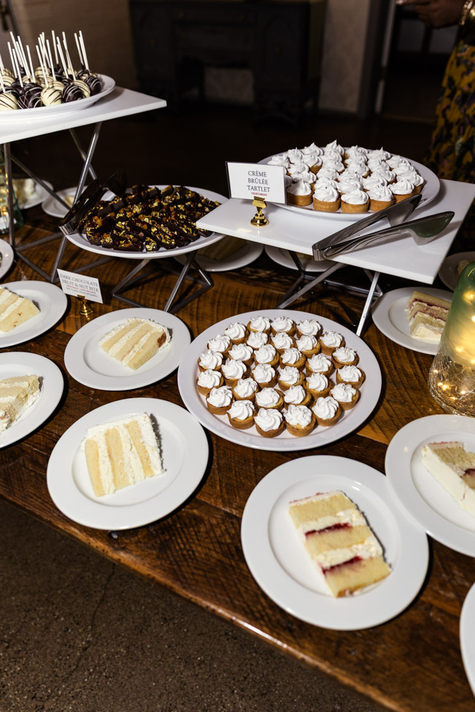 Dessert table for wedding reception at Firehouse Chicago with cupcakes, tarts, cake slices, cake pops, and a chocolate bark platter