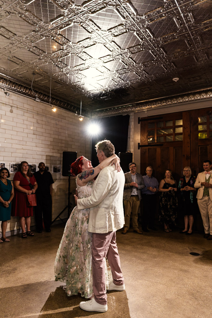 Newlywed couple shares a first dance at their Firehouse Chicago wedding reception surrounded by smiling guests