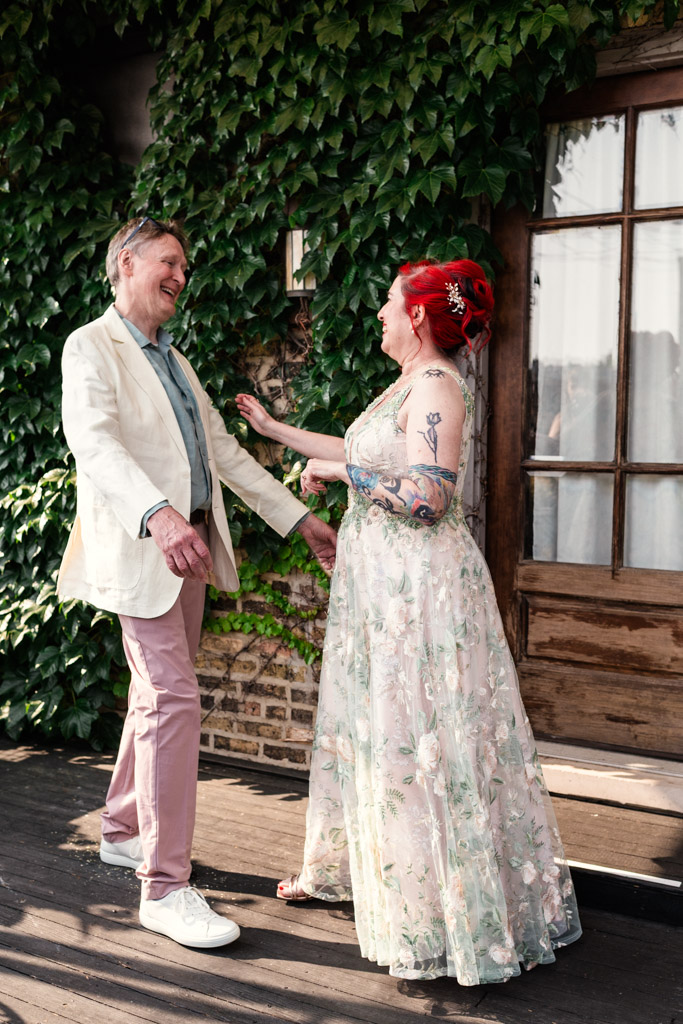 Bride and groom move toward each other outside on a wooden porch covered in ivy at Firehouse Chicago