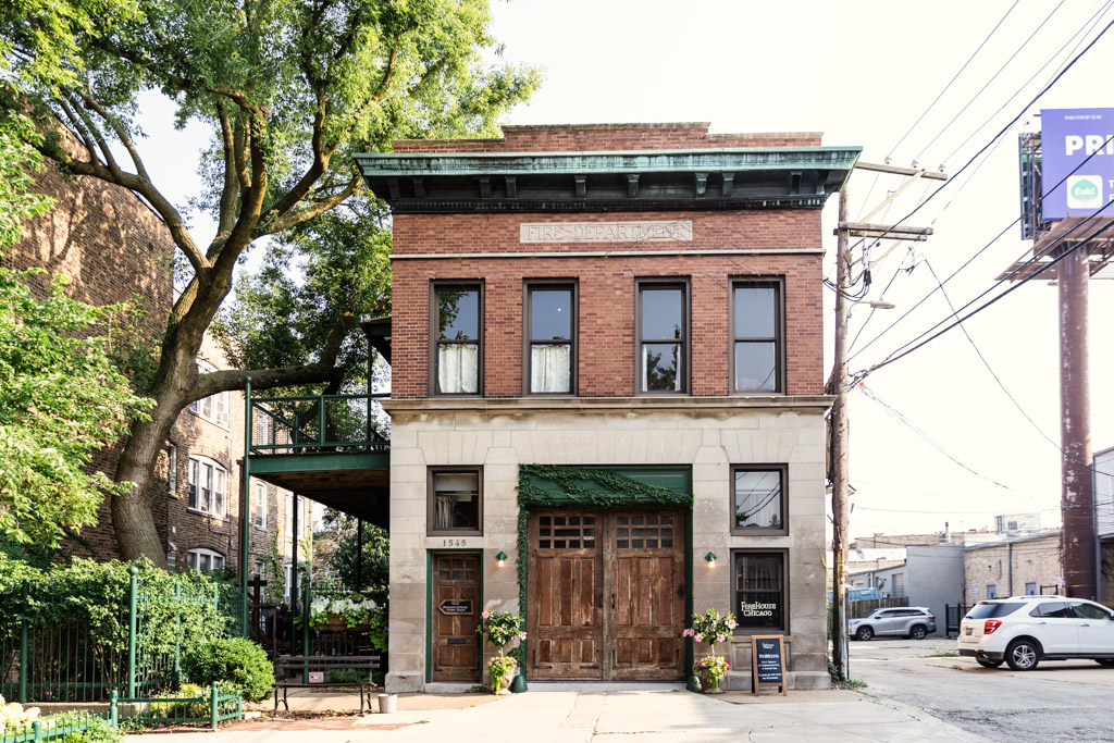 Exterior of Firehouse Chicago, a brick building with large windows, green doors, and a courtyard