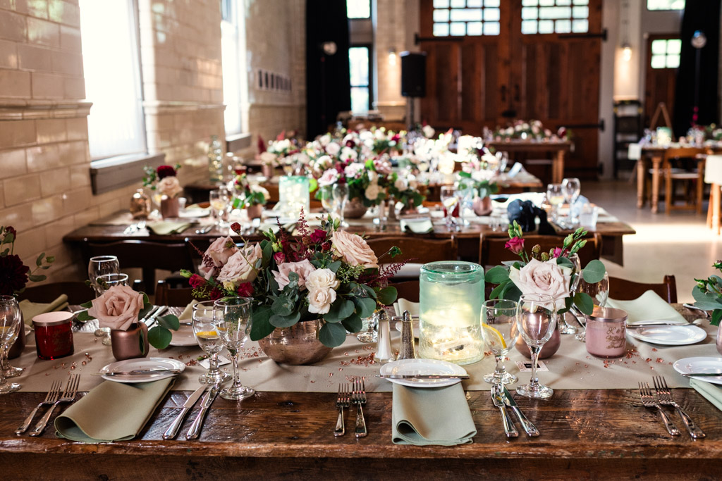 Guest tables set with flowers, candles, glassware, and pastel napkins in a bright room at Firehouse Chicago