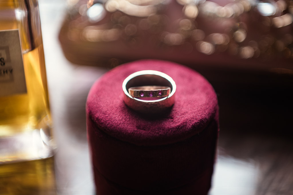Detail photo of gold ring with red stones rests on a round, burgundy velvet box, for wedding celebration at Firehouse Chicago