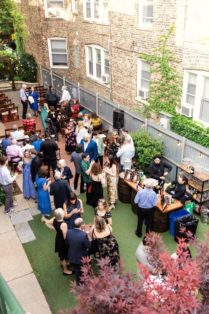 A crowd of people socializing at an outdoor party with food and drink stations set up along the historic brick walls of Firehouse Chicago.