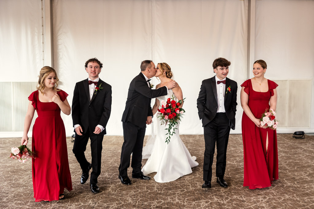 Bride and groom kiss at the Marriott Lincolnshire, flanked by bridesmaids in red dresses and groomsmen in black suits for Lincolnshire Marriott Resort wedding ceremony