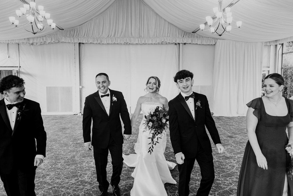 Bride, groom and their children in formal wear walk together, smiling at Lincolnshire Marriott Resort