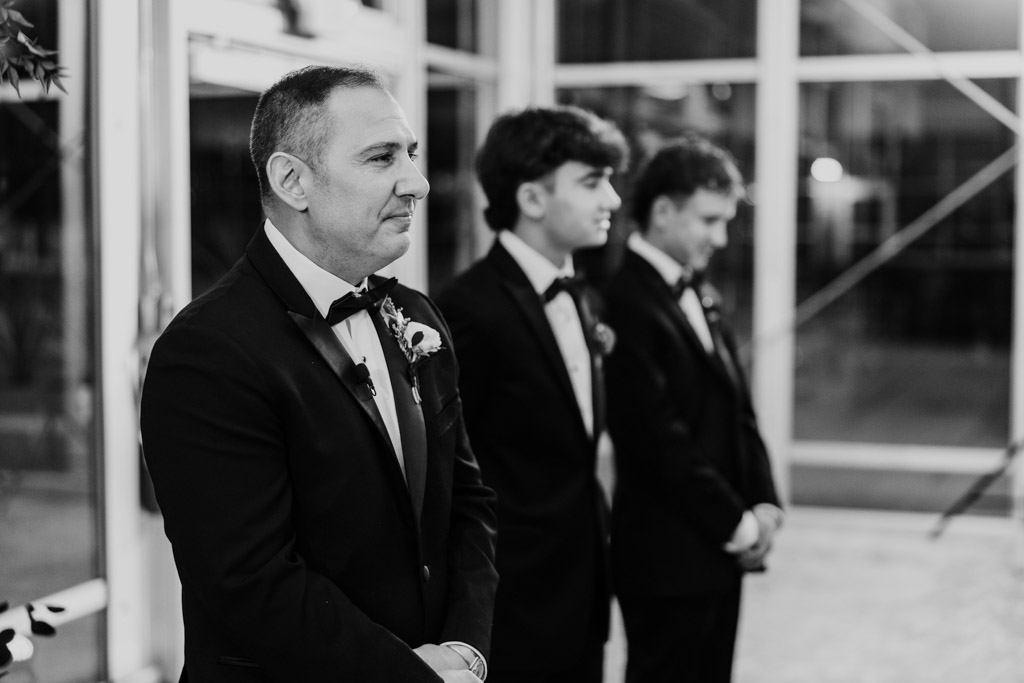 Black and white photo of groom and his wedding party in tuxedos standing in a row during weding ceremony at Lincolnshire Marriott Resort