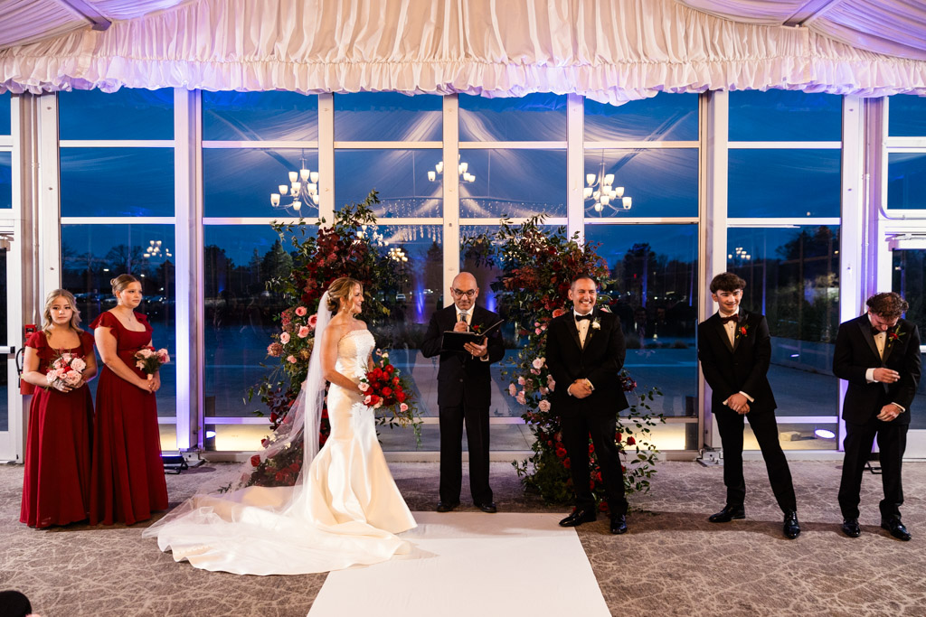 Bride and groom stand at the altar indoors with their wedding party and officiant, surrounded by flowers at Lincolnshire Marriott Resort