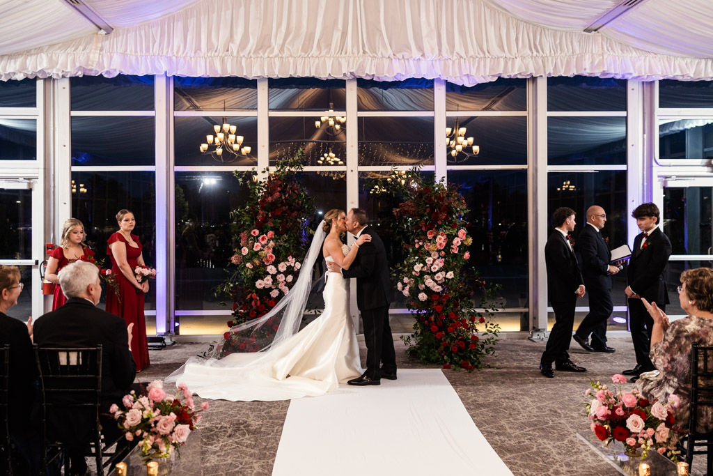 Bride and groom kiss during their wedding ceremony at Lincolnshire Marriott Resort, surrounded by flowers and applauding guests