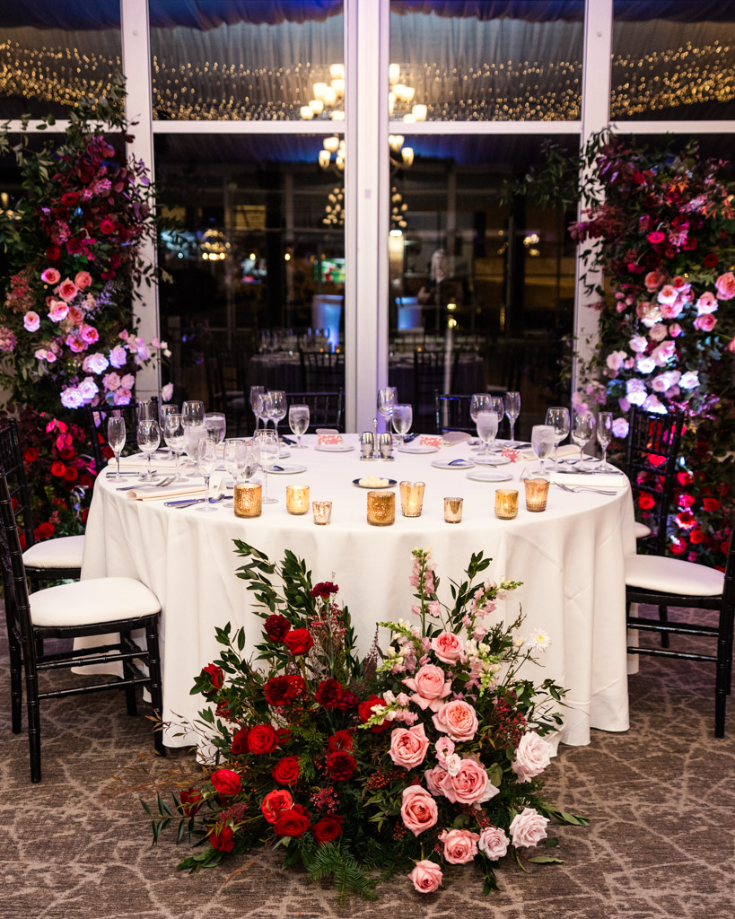 Rpund head table at Lincolnshire Marriott Resort wedding reception features candles, and pink and red flower arrangements