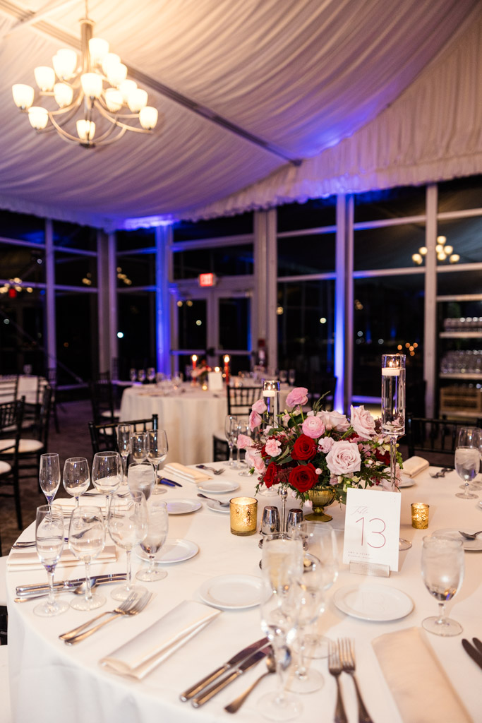Guest table with floral centerpiece, candles, glassware, and white tablecloths under a chandelier at Lincolnshire Marriott Resort wedding reception