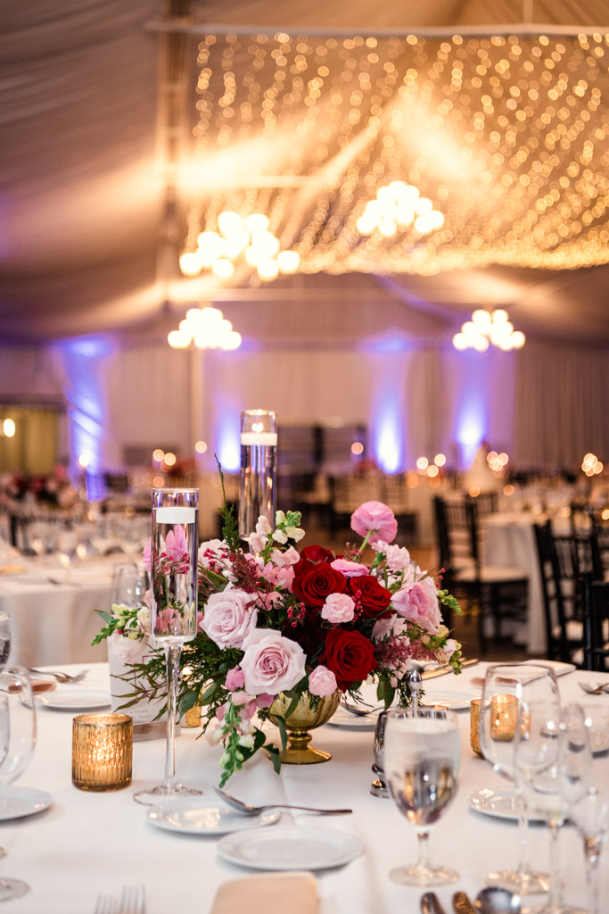 Guest table at Lincolnshire Marriott Resort, adorned with pink and red roses and candles, with string lights in the background