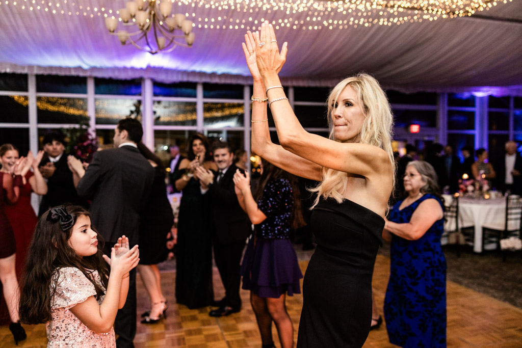 A woman in a black dress and a young girl clap hands on the dance floor during Lincolnshire Marriott Resort wedding reception