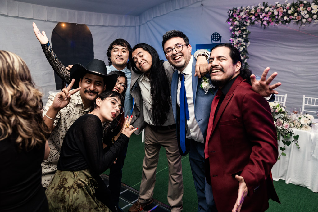 A group of people pose and smile at a Mexico City wedding reception under a decorated white tent.