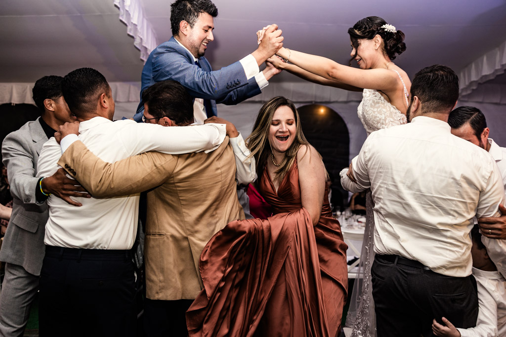 A bride and groom dance joyfully at their Mexico City wedding, surrounded by friends cheering and celebrating at a vibrant reception.
