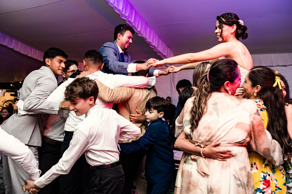 Guests lift newlyweds as they hold hands on the dance floor during mexico City wedding reception