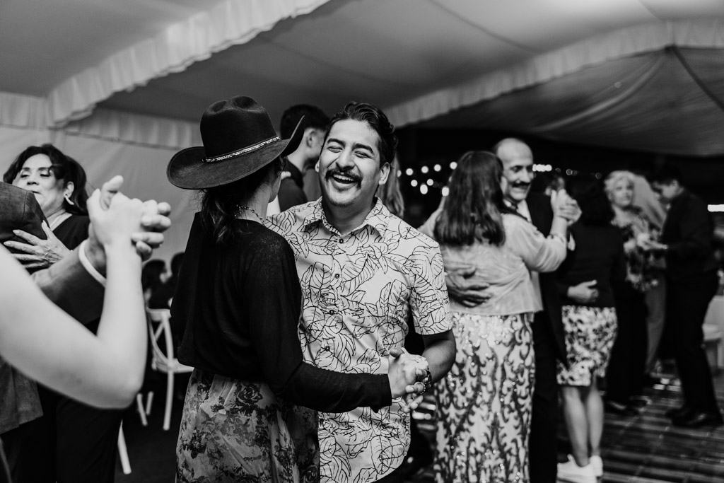 Black and white photo of guests dancing together under a tent at a festive Mexico City wedding