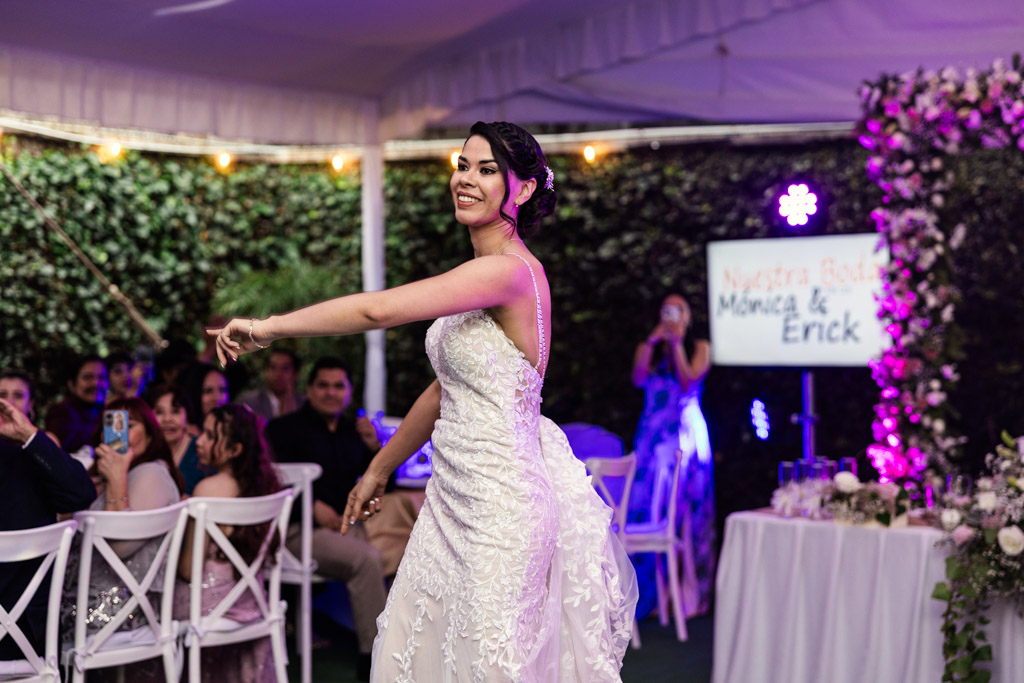 Bride in a white gown dances at her Mexico City wedding reception, smiling as guests watch and take photos