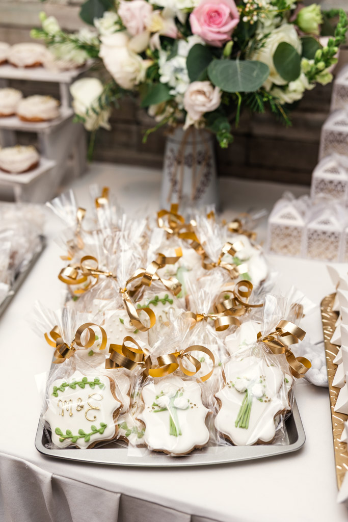 Tray of decorated cookies in clear bags with gold ribbons on a table for Mexico City wedding reception, with a floral bouquet in the background