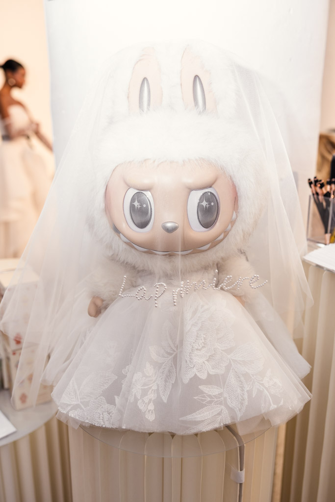 A cute rabbit doll dressed as a bride with a white lace veil and a fluffy hood over its ears, inspired by styles seen at New York Bridal Fashion Week.