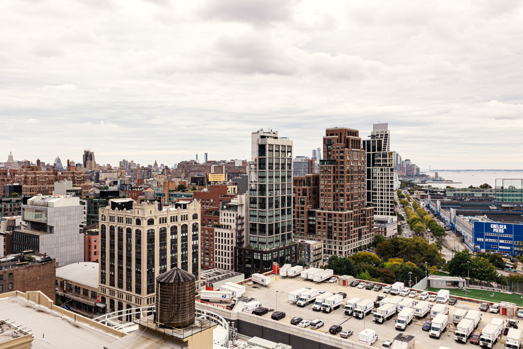 Cityscape view of modern and historic buildings, with a line of trucks parked below and a river in the background, capturing the bustling energy akin to New York Bridal Fashion Week.