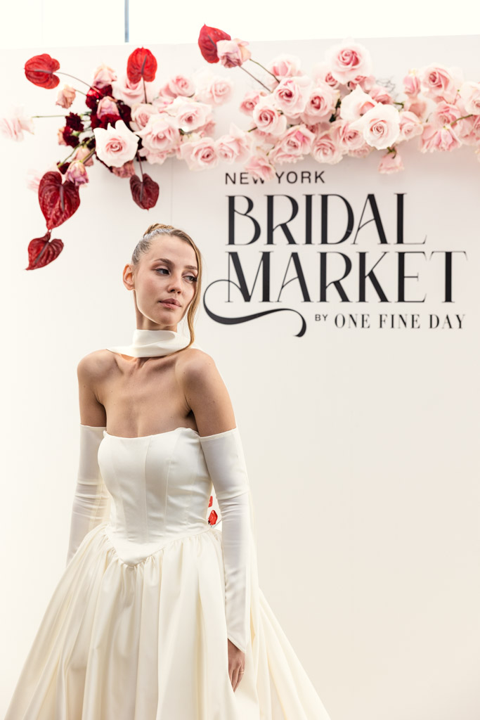 A woman in a white bridal gown stands in front of a