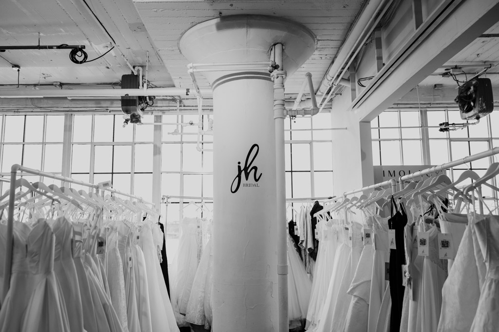 Racks of white wedding dresses surround a pillar with
