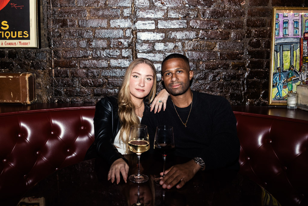 Portrait of engaged couple sitting closely together in a cozy restaurant booth with drinks at Emilio's Ballato